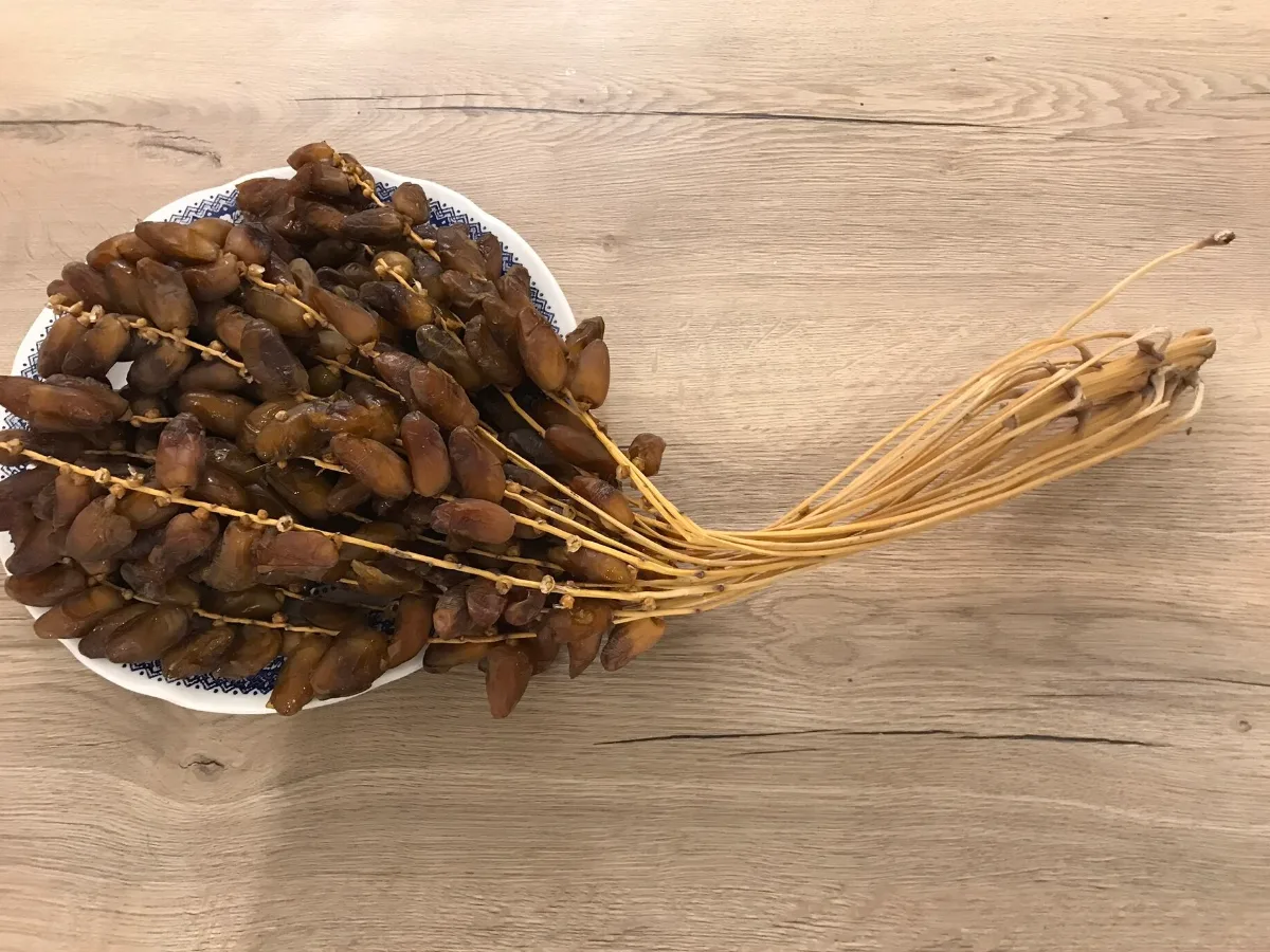 Dattes encore attachées à leurs branchettes, dans un bol sur une table en bois